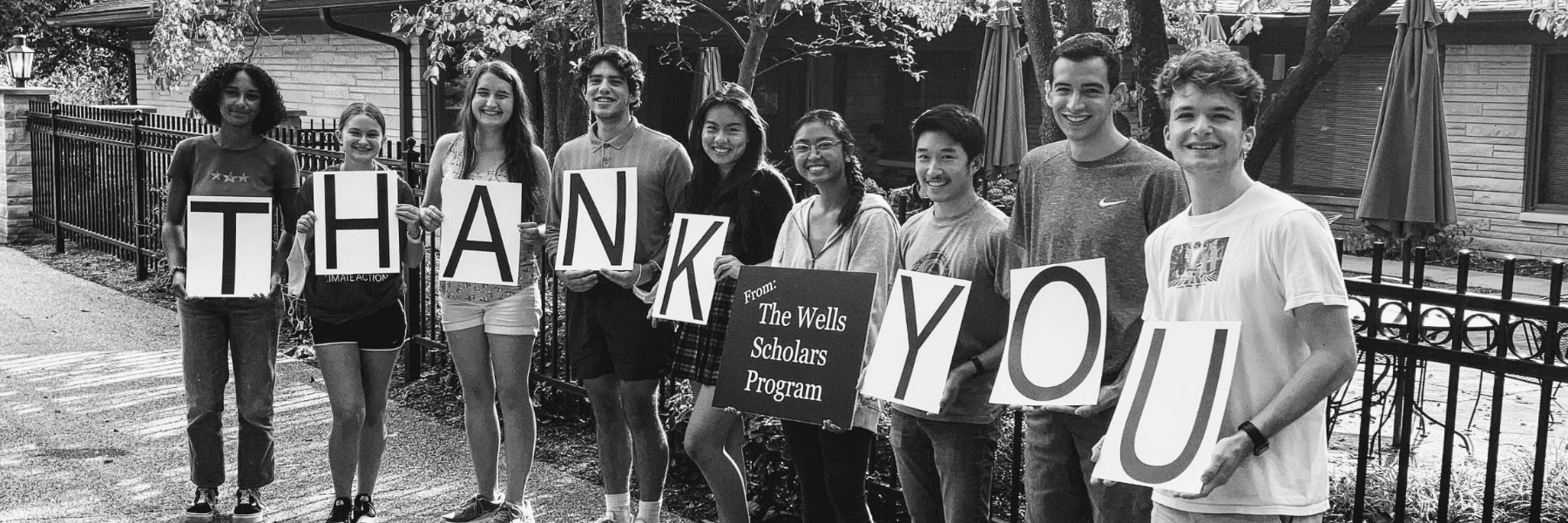 Image of Wells Scholars outside Harlos House holding signs that spell out Thank You.